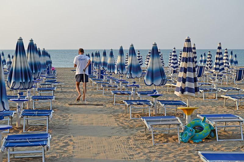Spiaggia con sabbia bianca e mare cristallino sotto un cielo azzurro.