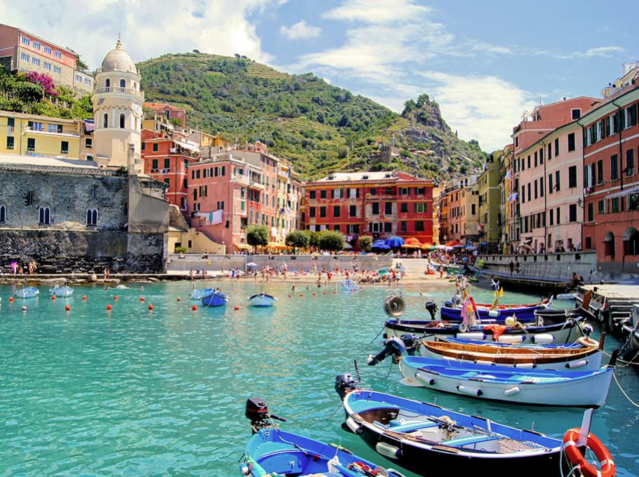 Vista costiera con mare turchese, spiaggia e città arroccata su una scogliera.